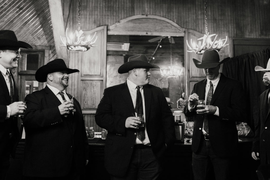 second photographers at wedding capture groomsmen at the bar