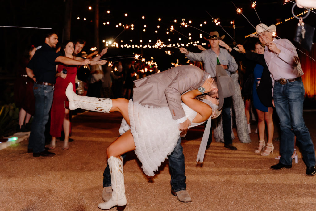 bride and groom kiss during sparkler exit at their western wedding at historic venue 