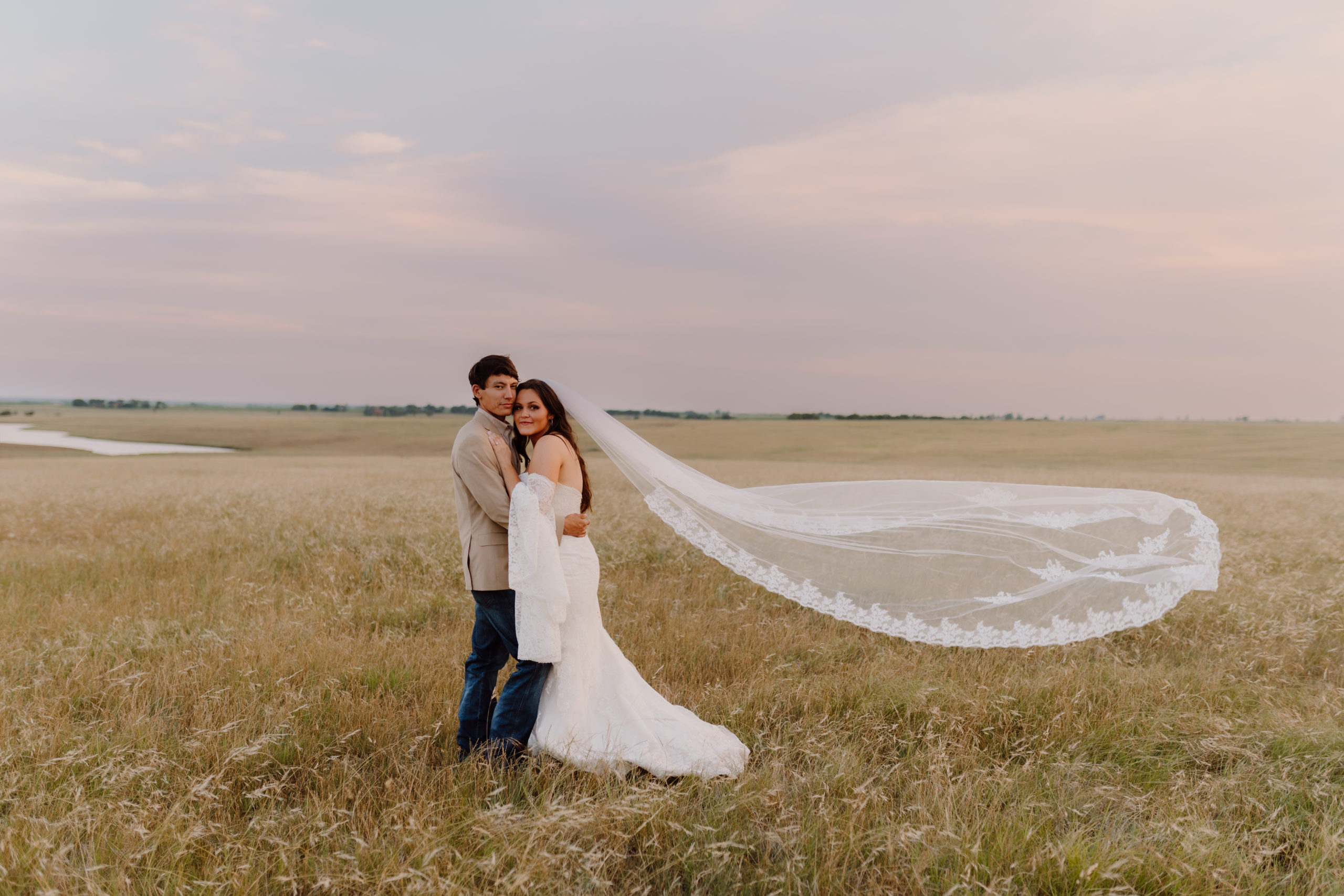 bride and groom hug in field