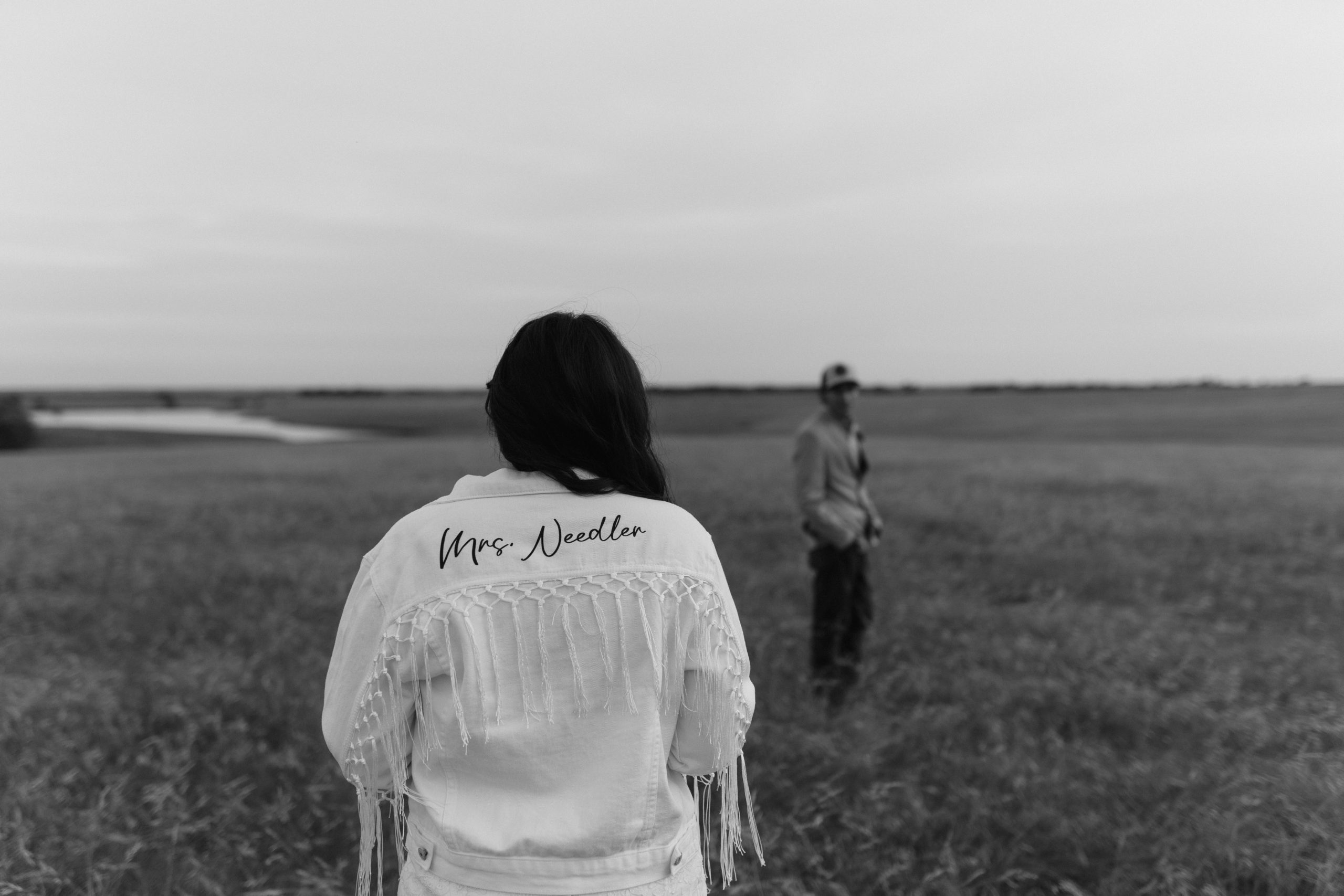 black and white image bride and groom in field